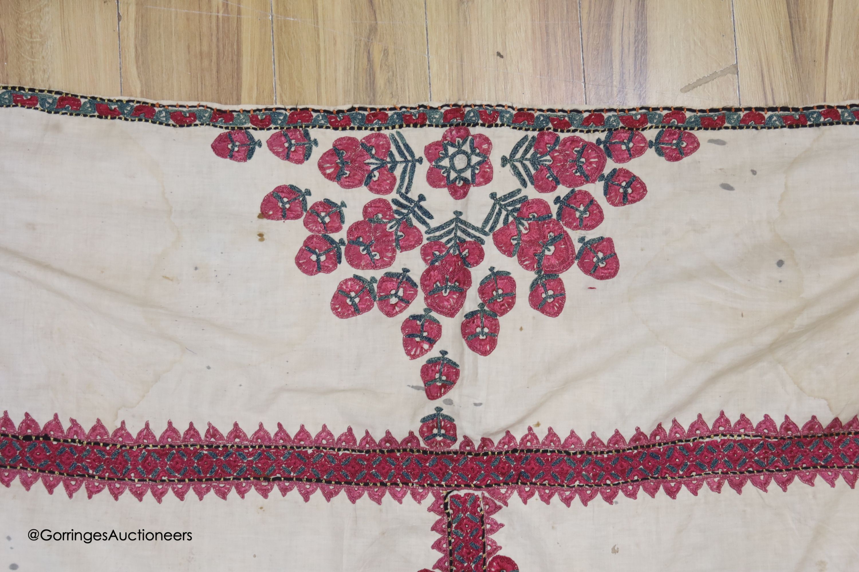 A silk embroidered Suzani, embroidered with cherry red flower heads with green stems and leaves in fine silk, width 134cm length 220cm